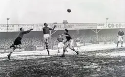 Stan Hanson fists the ball away as Mike Cullen rushes in