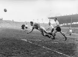 A diving headed clearance takes the ball away from Reg Pearce and Roy Davies