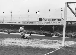 Harry Gregg dives bravely at the feet of Allan Brown