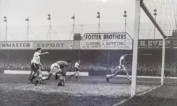 All eyes follow the path of the ball as Allan Brown sends this close range effort wide