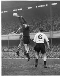 Ron Baynham puches the ball away under pressure from Vic Groves