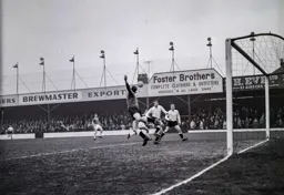 Ron Baynham leaps to save watched by Terry Kelly and Alan Daniel