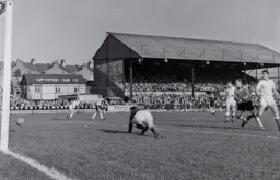 Ron Baynham scrambles to clear the ball