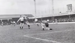 Colin Tinsley safely holds the ball while Gordon Fincham blocks off Ray Lancaster