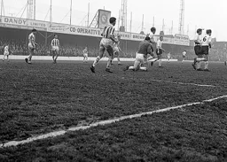United keeper Sandy Kennon breaks up an attack as John Moore races back into position