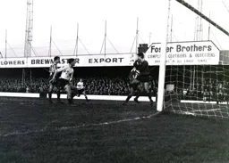 Brentford keeper Gordon Phillips safely handles the ball as Derek Kevan races in