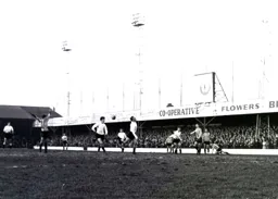 The ball goes between Bruce Rioch and Derek Kevan as Brentford appeal for offside