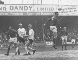 Keith Allen and Ian Buxton watch as the ball is headed clear by Peter Madden