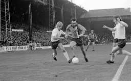John Aston worms his way between two Bolton defenders