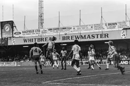 Ricky Hill watches on as defender heads clear