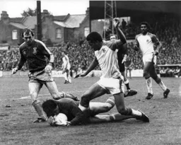 The keeper dives at the feet of Brian Stein