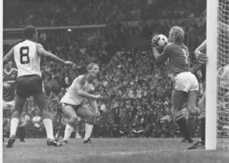 Gary Bailey gathers the ball, Paul Walsh looks for any possible slip up