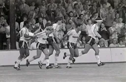 Brian Stein gets the congratulations of his teammates on scoring the first goal on the artificial surface