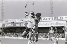 Steve Foster wins the heading duel with Gary Lineker watching on