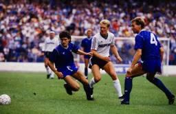 Tim Breacker is beaten the ball by Tony Dorigo