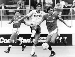 Bryan Robson moves the ball away from Mick Harford