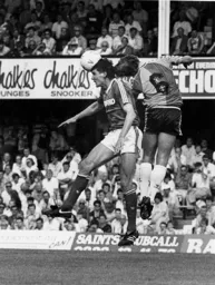 Russell Osman gets above Mick Harford wearing odd boots
