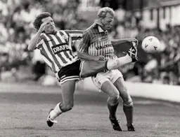 A high boot by Russell Osman knocks the ball away from Iain Dowie