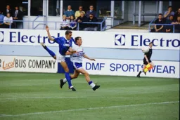 Steve Claridge with his trademark socks eases past the defender