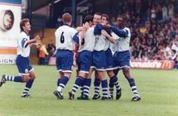 Steve Davis is surrounded by happy teammates after netting the second goal