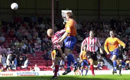 Steve Howard wins the header while Matthew Spring watches on