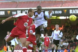 Tony Butler heads the ball away from Adrian Forbes