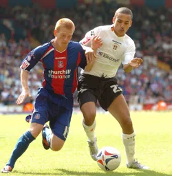 Dean Morgan challenges a Palace player for the ball