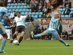 Steven Howard strikes as a Coventry defender lunges in