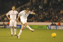 Peter Holmes strikes the ball watched by Chris Coyne