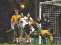 Marcus Heikkinen heads the ball in goalmouth action watched by Kevin Nicholls