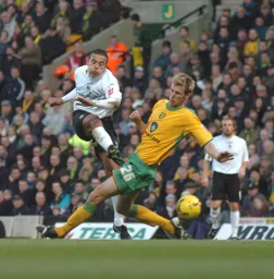 Carlos Edwards takes strike under pressure from a Norwich player