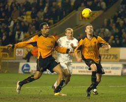 Warren Feeney tries to get to the ball bewteen two Wolves players