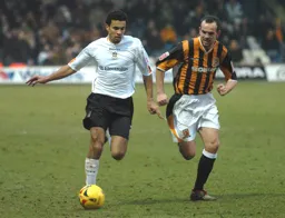 Carlos Edwards, ball at his feet, pursued by a Hull player