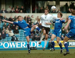 Peter Holmes heads the ball under pressure from three Milwall players