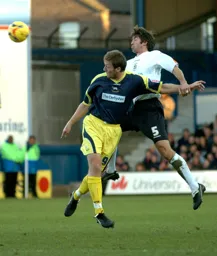Russell Perrett heads the ball clear from Steve Howard