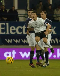 Steve Robinson with both feet off the ground fires a shot at goal
