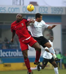 Lewis Emanuel challenges for the ball with Dele Adebola