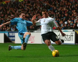 Lewis Emanuel gets in a cross as a lunging tackle comes in