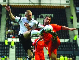 Lewis Emanuel and Gary Teale appear to get their foot on the ball at the same time