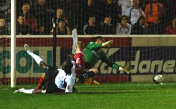 The ball rolls goalward as Paul Furlong slides across the pitch