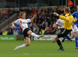 Rossi Jarvis forcing the goalkeeper into a hurried clearance
