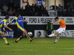 Tom Craddock shoots as former Hatter Ian Roper attempts to block it