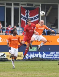 Paul Carden wins this battle to the delight of the Hatters Norwegian fans in the background