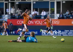 Stuart Fleetwood knocks the ball past the grounded Ben McNamara
