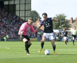 Danny Hylton attempts to dribble the ball past Paul Farman