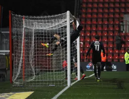 Danny Hylton swings from the crossbar after former Hatter Matt Taylor had put through his own goal