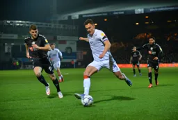 Kal Naismith about to whip in a ball under the watchful eyes of former Hatters Chris Martin and Jay Da Silva