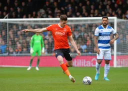Reece Burke sends a long ball down the line, former Hatter Andre Gray is applying pressure