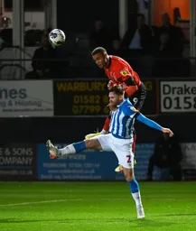 Carlton Morris gets above Ollie Turton to head the ball into the penalty area