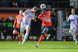 Ben Gibson heads the ball clear as Elijah Adebayo rushes in
